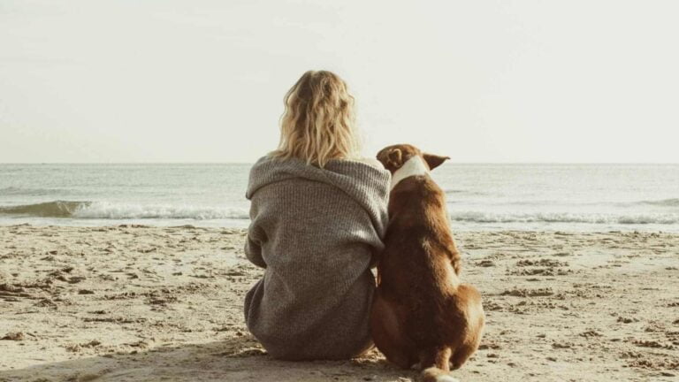 Woman and companion dog on beach